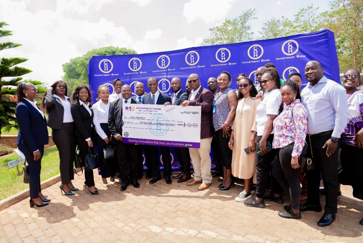 CDH Investment Bank staff, UNC Project staff and representatives from Dzama Educational Development Program celebrate and pose with the symbolic cheque. 